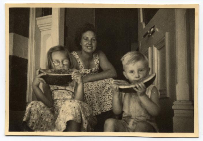 Nonja and her brother eating watermelon on their door step